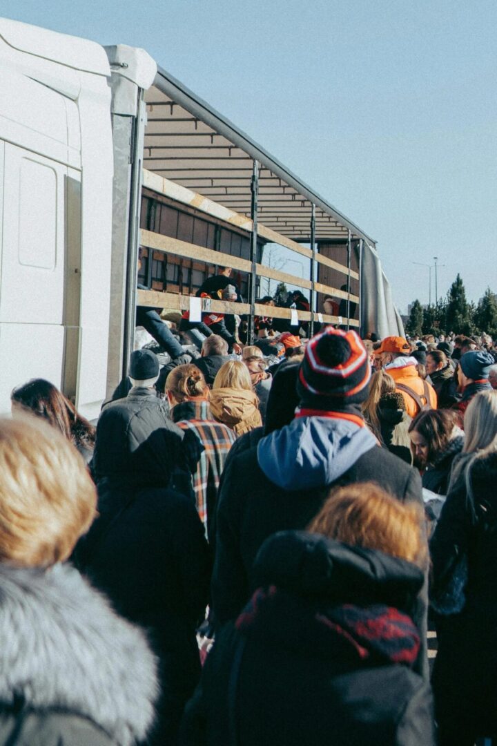 People queuing outside on a sunny day.